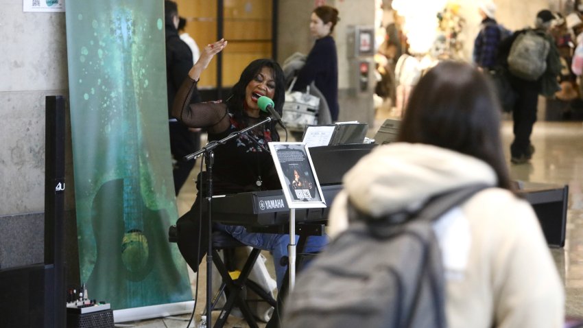 CORRECTS SPELLING OF SINGERS LAST NAME TO MCCOMMON – Roz McCommon performs amid travelers at Seattle-Tacoma International Airport on November 26, 2024, in SeaTac, Wash.