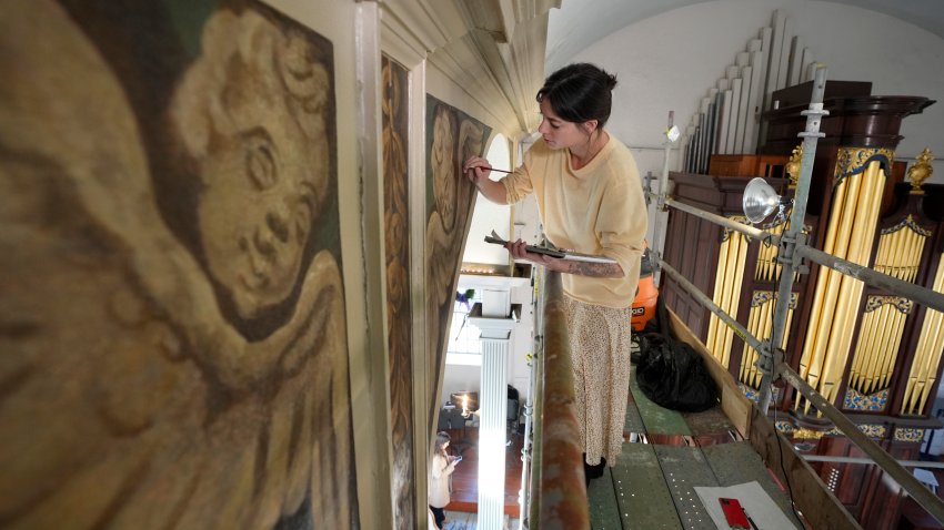 Conservator Corrine Long, of Dover, N.H., restores nearly 300-year-old painted angels on walls of Old North Church, Wednesday, Dec. 18, 2024, in Boston. (AP Photo/Steven Senne)