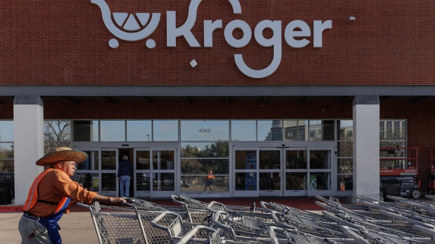 A worker pushes shopping carts outside a Kroger grocery store