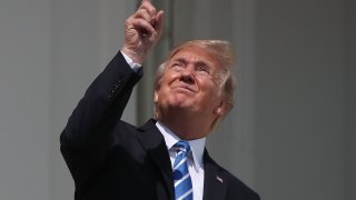 File - Then-President Donald Trump points at a partial solar eclipse from the balcony of the White House in Washington, DC, on August 21, 2017.