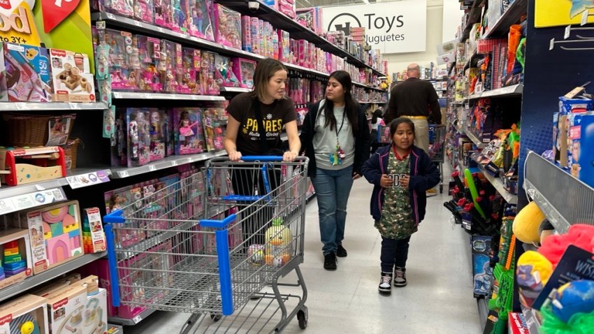 Madison Taylor-Hawk, with San Diego Padres ball park operations (left) helps Julianna Torres (center) and Chelsey Torres, 6, pick out gifts, Friday morning,