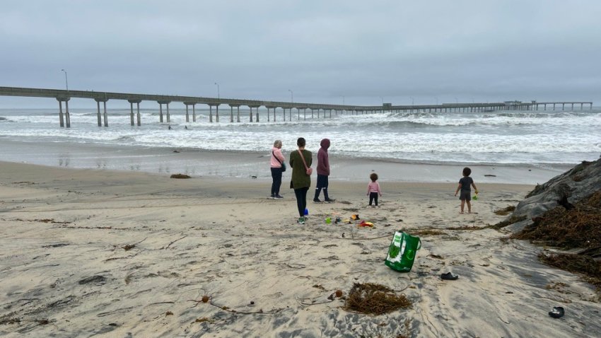 A family enjoys Ocean Beach as the iconic pier remains closed on Dec. 28, 2024. (NBC 7 San Diego)