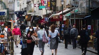 Pedestrians wear protective face masks while passing stores and cafes on Rue Montorgueil in Paris, France, on Wednesday, Aug. 26, 2020.