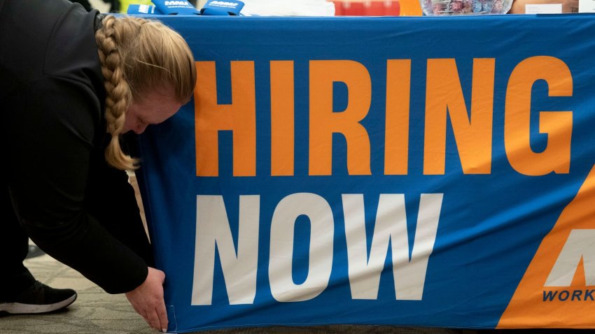 A worker adjusts hiring signage at a job and resource fair hosted by the Mountain Area Workforce Development Board in partnership with NCWorks in Hendersonville, North Carolina, US, on Tuesday, Nov. 19, 2024. 