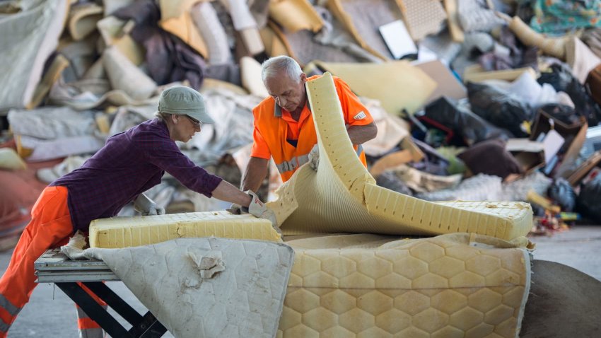 Workers dismantling a mattress.