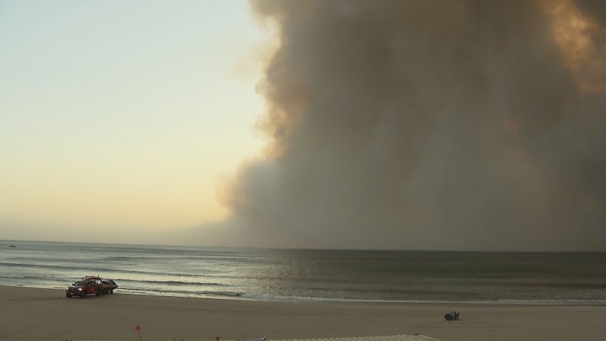 Smoke hangs over the water near a beach