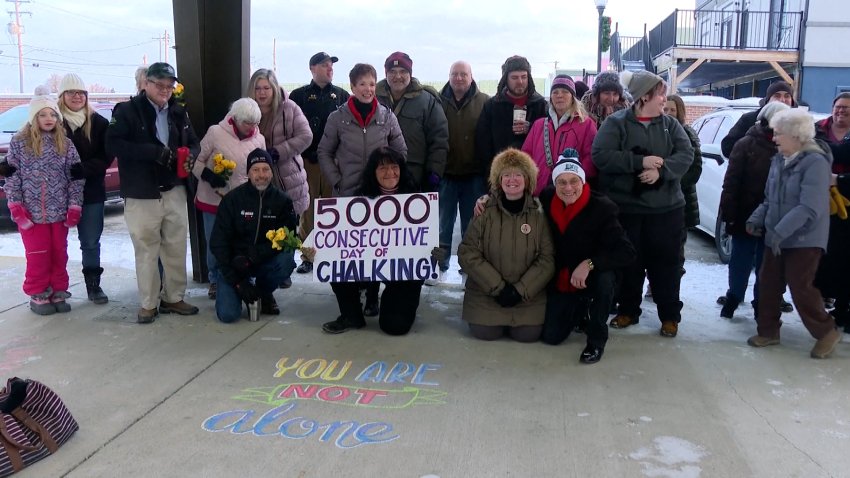 A group of people posing by sidewalk chalk art.