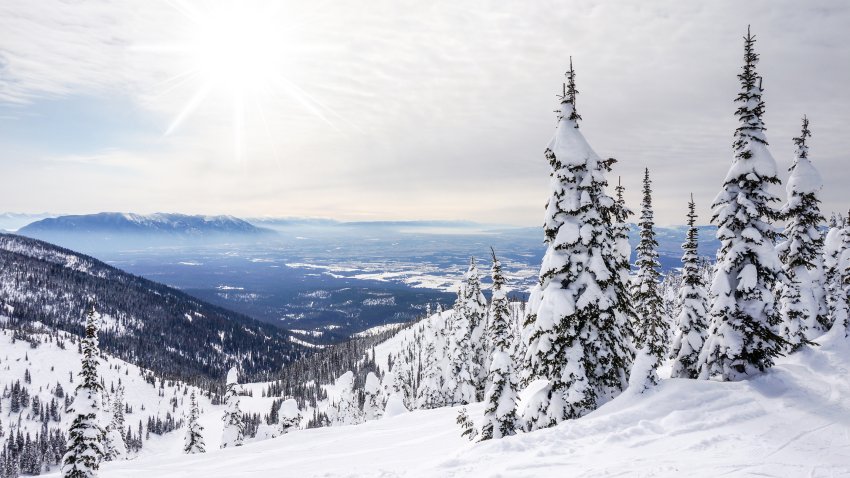 White winter landscape against the sun with fluffy clouds in Whitefish, Montana