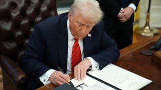 Donald Trump signs an executive order in the Oval Office of the White House on Feb. 10.
