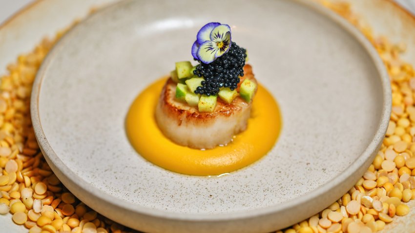 Gourmet scallop dish with edible flower and caviar garnish