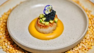 Gourmet scallop dish with edible flower and caviar garnish
