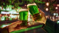 Two people sitting in pub at bar counter and drinking craft green traditional beer