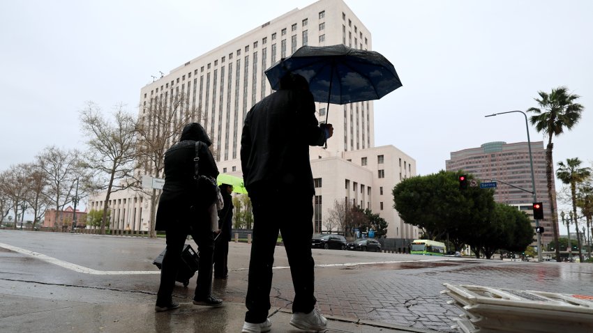 Pedestrians navigate the rain as they cross the street in downtown Los Angeles.