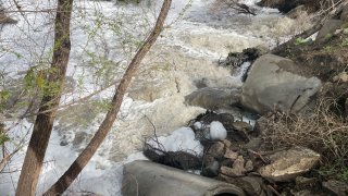 Foamy dirty water discharges into a river.