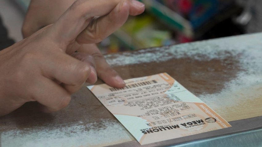 A woman crosses her fingers after purchasing a Mega Millions lottery ticket.
