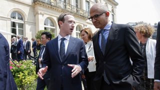 Facebook’s CEO Mark Zuckerberg (L) speaks with Microsoft’s CEO Satya Nadella after posing for a family picture with guests who attend the “Tech for Good” Summit at the Elysee Palace in Paris, on May 23, 2018.