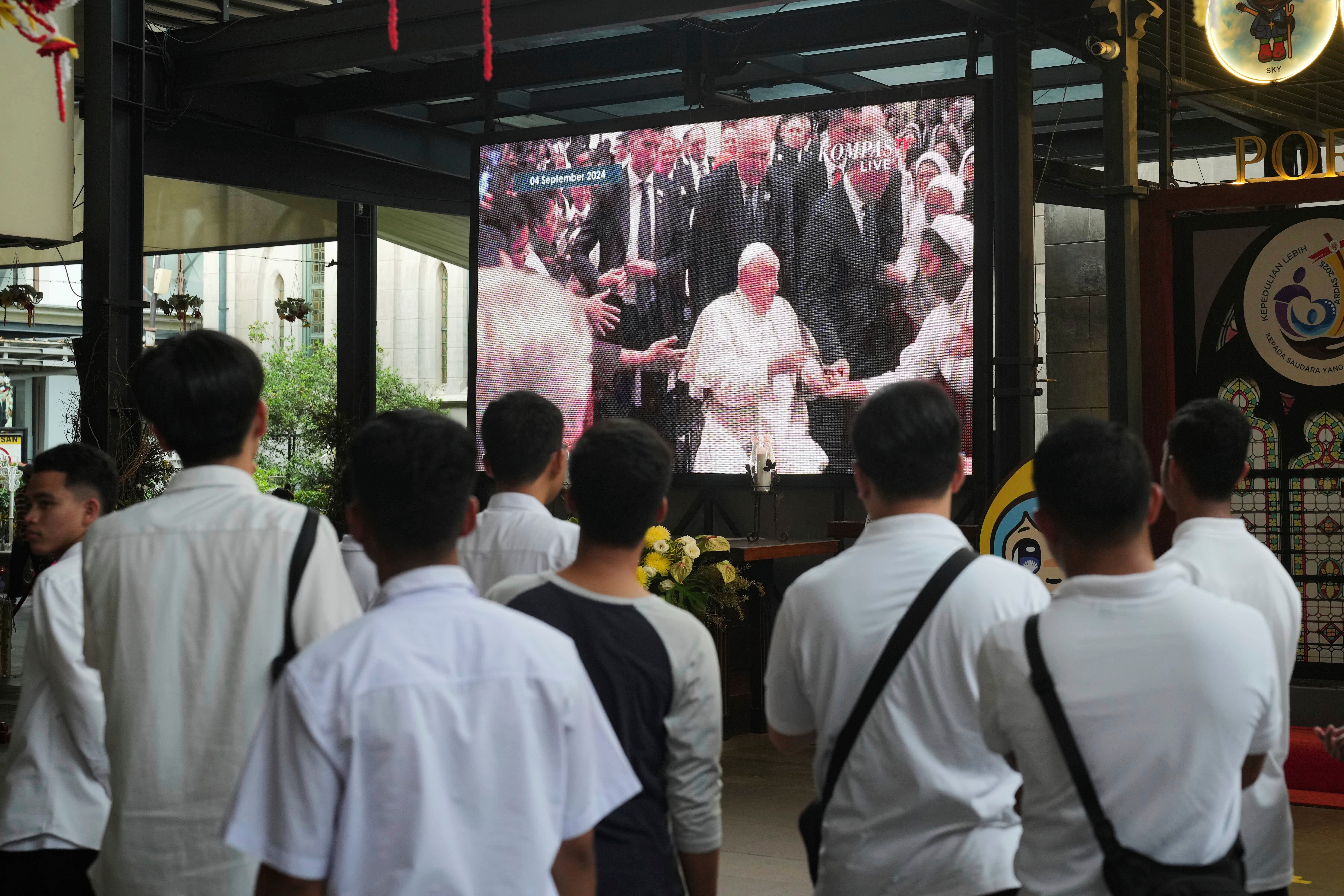 People watch a video recording of Pope Francis’ 2024 visit to the Church of Our Lady of the Assumption, in Jakarta, Indonesia, Monday, April 21, 2025.