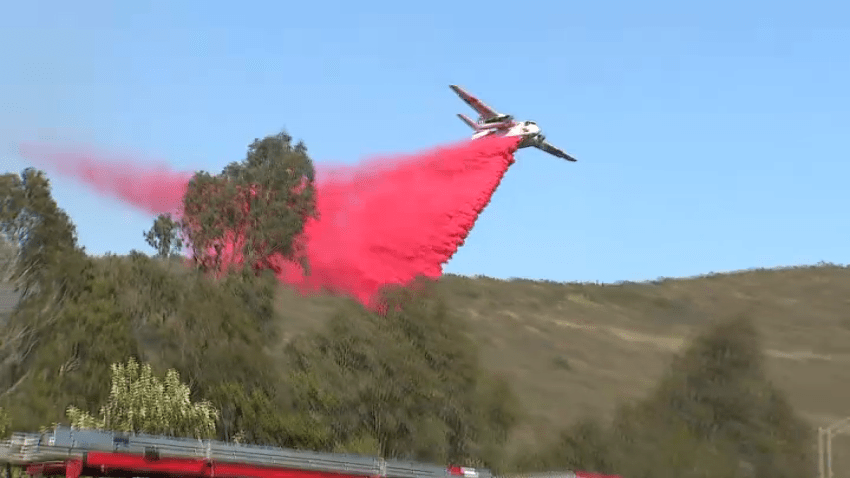 An aircraft drops fire retardant on a brushfire in Poway, May 24, 2025.