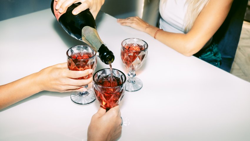 Unrecognizable female friends celebrate and drink red sparkling wine