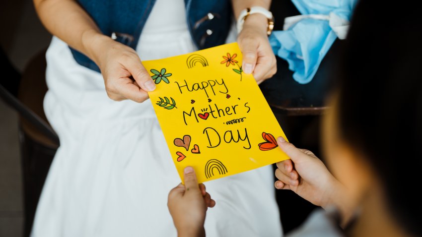 Close-up of woman receiving greeting card from her son on Mother's day.