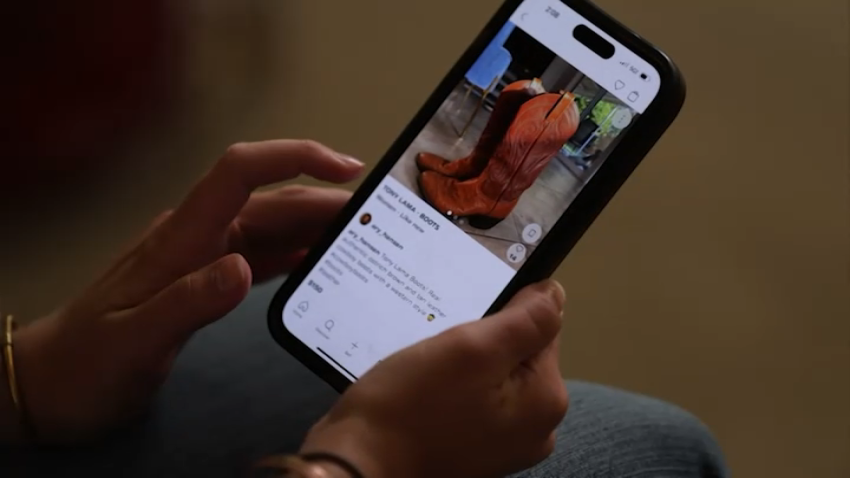 A person's phone showing boots for sale on a shopping app.