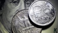 A Russian ruble coin with a U.S. dollar bill and a quarter dollar coin in Moscow, on Oct. 10, 2023.