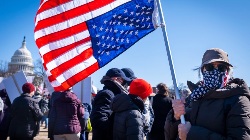 A federal employee who asked not to be named holds an U.S. flag that she flew upside down "as a sign of distress," during the "No Kings Day" protest on Presidents Day in Washington.