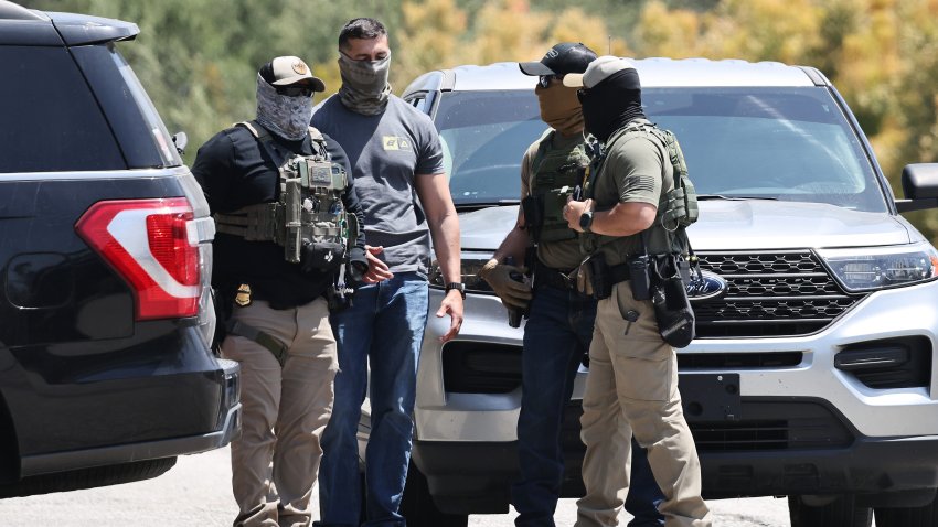 LOS ANGELES, CALIFORNIA – JUNE 19: An LAPD officer walks near masked federal agents staged outside a gate of Dodger Stadium on June 19, 2025 in Los Angeles, California. The Los Angeles Dodgers said in a statement that federal ICE agents requested permission to access Dodger Stadium parking lots but were denied entry. (Photo by Mario Tama/Getty Images)