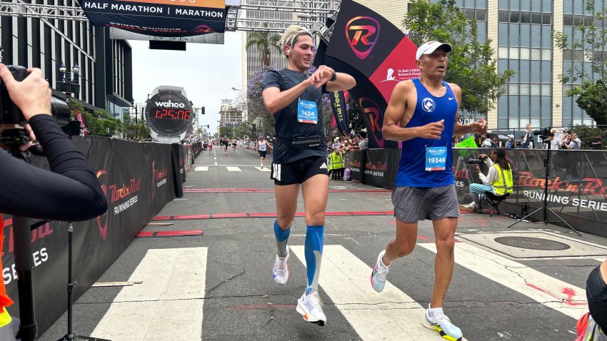 Two runners cross the finish line of the half marathon, Sunday morning. The course took them through eight neighborhoods in central San Diego. June 1, 2025.