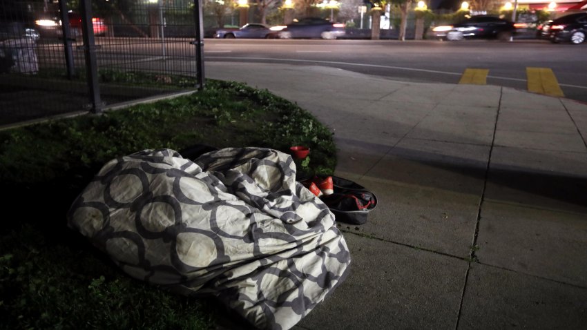 A homeless person, with only a sheet for shelter