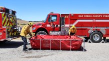 Firefighters demonstrate the use of a 2,000 gallon tank. It is kept on a water tender truck to expedite water flow. Photo provided by CAL FIRE San Diego County.
