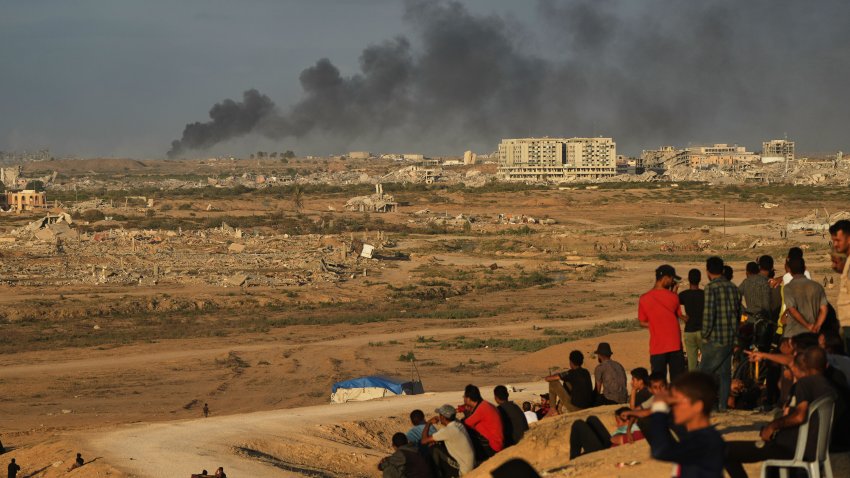 Displaced Palestinians watch smoke rise after Israeli military strikes as they gather on the coastal road near Wadi Gaza, in the central Gaza Strip, Thursday, Oct. 9, 2025.