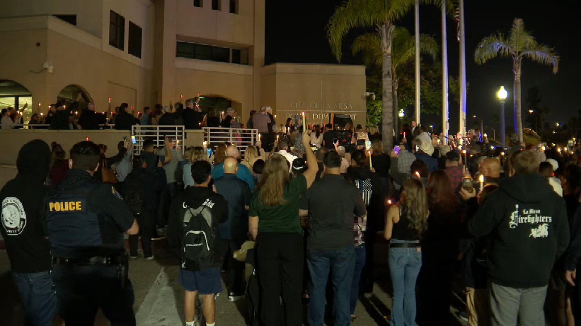 People hold up candles to honor La Mesa police Officer Lauren Craven during a vigil at police headquarters on University Avenue on Oct. 27, 2025.