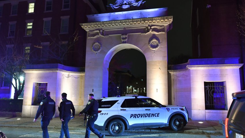 Law enforcement officials walk near an entrance to Brown University in Providence, R.I., on Saturday, Dec. 13, 2025, during the investigation of a shooting.