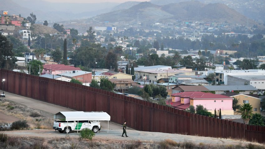 A US Border Patrol agent walks toward the fence separating the United States and Mexico near Jamul, California on Nov. 8, 2021, across from the Baja California city of Tecate, Mexico.