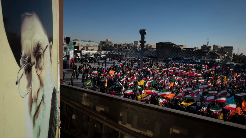 Iranian people hold the national flags next to a portrait of Iran’s Supreme Leader, Ayatollah Ali Khamenei, during a pro-government rally in southern Tehran, Iran, on December 30, 2025.