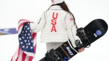 Chloe Kim of the United States walks with her snowboard and an American flag after winning silver in the women's halfpipe final.