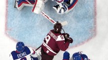 Renars Krastenbergs of Latvia scores their first goal past Connor Hellebuyck of United States in men's ice hockey group C play.