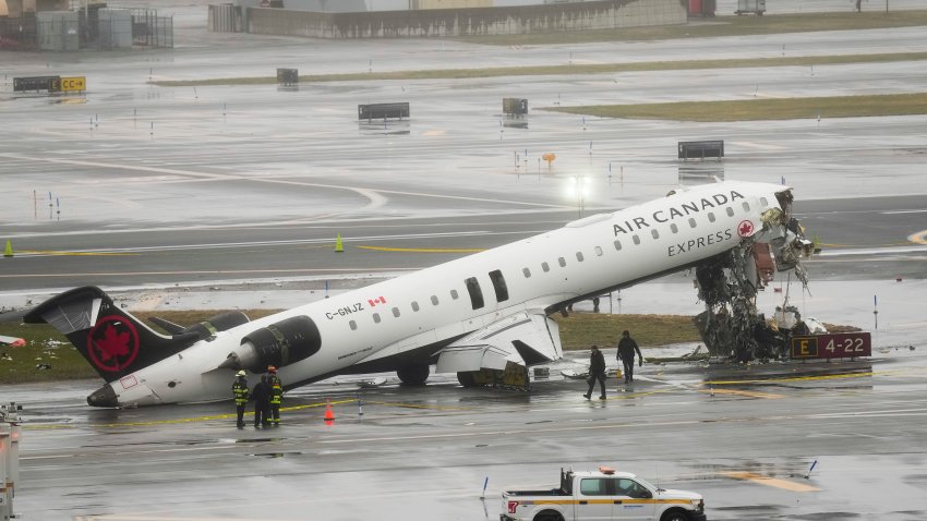 Firefighters and investigators examine the site, Monday, March 23, 2026, where an Air Canada jet came to rest after colliding with a Port Authority firetruck at LaGuardia Airport, after landing Sunday night in New York.