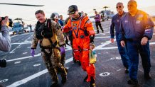 NASA astronaut Reid Wiseman walks with NASA personnel on the flight deck of the San Antonio Class amphibious transport dock USS John P. Murtha (LPD 26) after returning from space on Apr. 10, 2026. John P. Murtha is underway in the U.S. 3rd Fleet area of operations supporting NASA’s Artemis II mission, retrieving the crew and spacecraft following their return to Earth and splashdown in the Pacific Ocean. NASA’s Artemis II mission sent four astronauts on a flight around the moon in the Orion space craft,