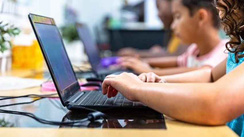 Elementary students use computers in a classroom.