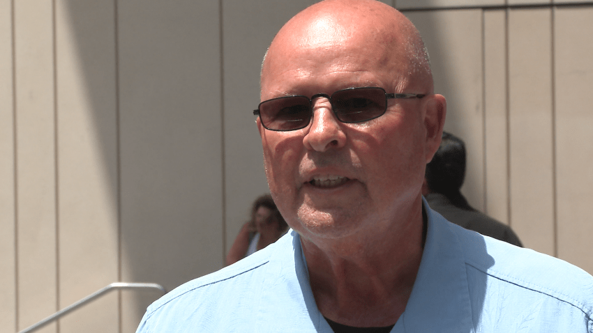 Bald man with sunglasses and a blue shirt.