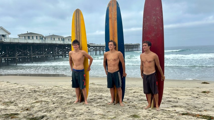 (L-R) Waylen Chanzer, Rex Mehran, and Trevor Holloway  display their ‘old school’ surfboards, Saturday, before competing in the OMBAC Classic fundraiser, September 12, 2026.